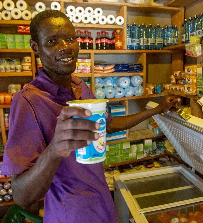 Smiling man holding a cold drink from a refrigerator